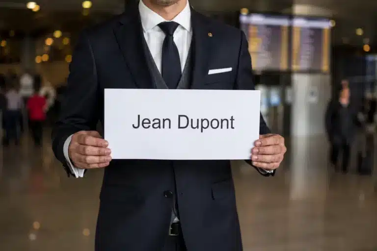 Chauffeur avec pancarte nominative dans le hall des arrivées de TLN — taxi aéroport Toulon-Hyères AP Prestige Driver
