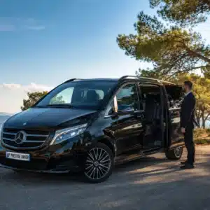 Chauffeur privé AP Prestige Driver ouvrant la Mercedes Classe V noire avec vue sur la Méditerranée, Var